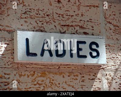 Insegna del bagno per signore in un parco. Edificio vecchio e dal design caldo. Foto Stock
