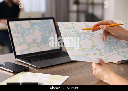 Cartografo che lavora con mappe catastali al tavolo di legno in ufficio, primo piano Foto Stock