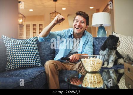 Festeggiamenti, uomo e televisione o popcorn a casa sul divano con guardare una partita di sport, una sfida e un divertimento. Soggiorno, divano, eccitato o felice Foto Stock