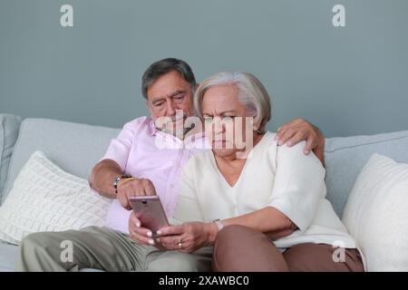 La coppia anziana controlla il cellulare a casa Foto Stock