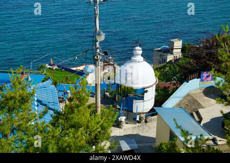 Donghae City, Corea del Sud - 18 maggio 2024: Una pittoresca vista di Nongoldam Street, caratterizzata da tetti blu vibranti e da una vecchia struttura faro, W Foto Stock
