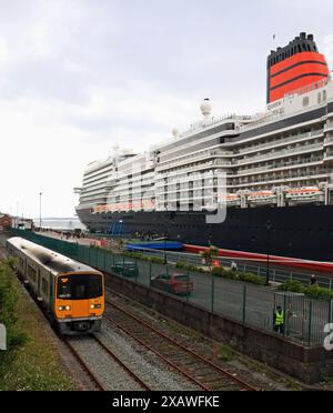 Un treno sminuito dalla nave da crociera Cunard la “Queen Anne” ormeggiata in porto per il giorno, lascia la stazione di Cobh per un servizio verso Cork. Foto Stock