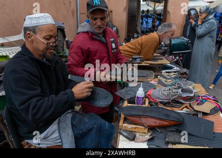 Marrakech, Marocco - 23 marzo 2024: Calzolai tradizionali nel suk della medina di Marrakech incollando nuove suole su vecchie scarpe Foto Stock