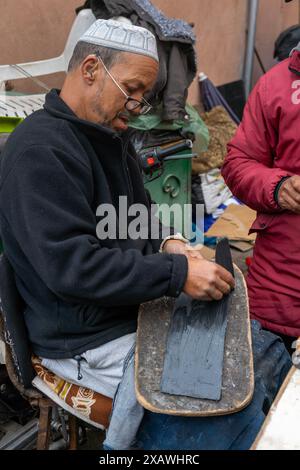 Marrakech, Marocco - 23 marzo 2024: Calzolai tradizionali nel suk della medina di Marrakech incollando nuove suole su vecchie scarpe Foto Stock