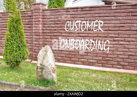 Concetto di business. Simbolo DI ONBOARDING DEL CLIENTE su una recinzione di mattoni rossi Foto Stock