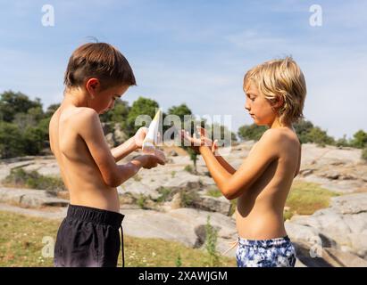 Due bambini caucasici che indossano la crema solare in natura Foto Stock