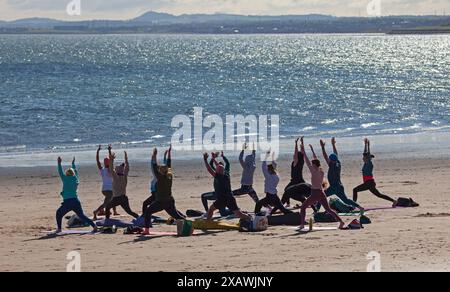 Portobello, Edimburgo, Scozia, Regno Unito. 9 giugno 2024. Vento fresco ma soleggiato a Portobello vicino al Firth of Forth per chi è sulla spiaggia e sull'acqua, temperatura 13 gradi centigradi. Nella foto: Yoga fresco sulla spiaggia sabbiosa vicino al Firth of Forth. Credito: Arch White/alamy notizie dal vivo. Foto Stock