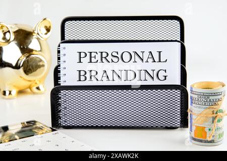 Concetto di business. Testo di branding personale su un foglio vuoto in una composizione con un salvadanaio e un rotolo di dollari Foto Stock