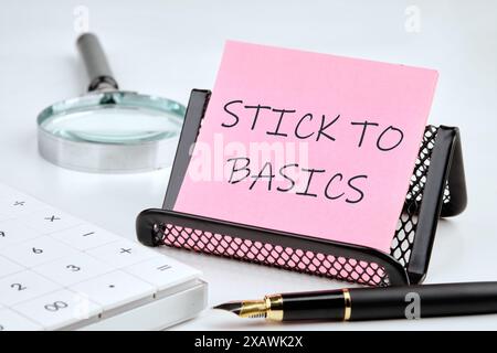 Concetto di business. Il testo SI ISPIRA ALLE NOZIONI DI BASE scritte su un adesivo rosa su un piedistallo nero su sfondo bianco Foto Stock