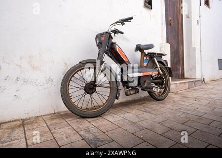 Una piccola vecchia motocicletta nera tipica è parcheggiata appoggiata contro il muro in una strada nella Kasbah delle Oudayas a Rabat, capitale del Marocco Foto Stock