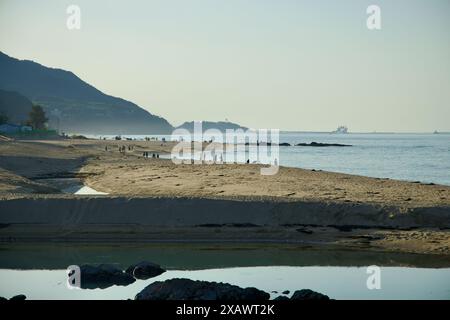 Gangneung, Corea del Sud - 18 maggio 2024: I visitatori passeggiano lungo le spiagge sabbiose di Jeongdongjin Beach mentre il sole tramonta, proiettando un sereno bagliore sul Foto Stock