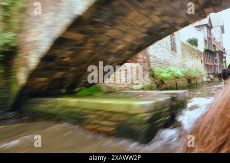 Uno scatto dinamico da una barca che si muove sotto un ponte in un canale tranquillo Foto Stock