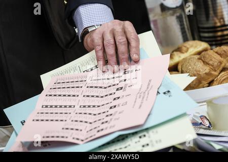 Una persona riceve le tre schede elettorali in una stazione elettorale di Namur, domenica 9 giugno 2024. Il Belgio tiene le elezioni per gli organi legislativi regionali, federali ed europei. FOTO DEL BELGA BRUNO FAHY Foto Stock