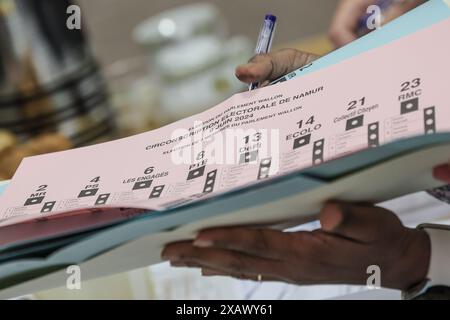 Una persona riceve le tre schede elettorali in una stazione elettorale di Namur, domenica 9 giugno 2024. Il Belgio tiene le elezioni per gli organi legislativi regionali, federali ed europei. FOTO DEL BELGA BRUNO FAHY Foto Stock