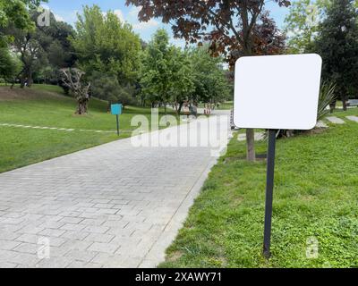 Mockup, vista laterale vuota o cartellone bianco bianco con percorso nel parco in primavera o in estate. Lavagna bianca vuota per informazioni e indicazioni nel parco, con una Foto Stock