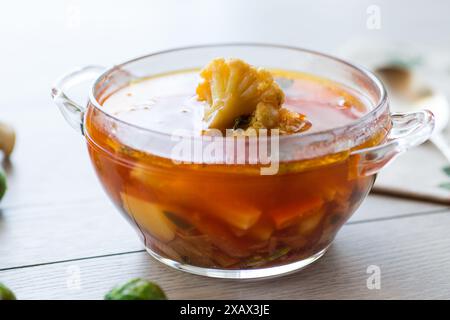 Zuppa di verdure con cavoletti di Bruxelles e cavolfiore, in un piatto di vetro su un tavolo di legno. Foto Stock