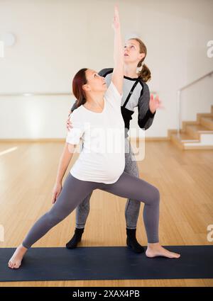 Donna che fa yoga con istruttore Foto Stock