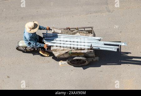 Un uomo porta tubi su una bicicletta con una carriola, Saigon, Vietnam Foto Stock