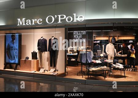 Marco o Polo Fashion Store am Flughafen München. DAS Modelabel Marc o Polo wurde 1967 von den Schweden Rolf Lind, Goete Huss und dem US-Amerikaner Jerry o Sheets a Stoccolma gegründet. Kern der Markenidentität ist die Verwendung natürlicher Materialien. Die deutsche Tochtergesellschaft Marc o Polo Deutschland wurde im Jahr 1968 durch Werner Böck mit Sitz in Stephanskirchen im Landkreis Rosenheim gegründet. Im Jahr 1987 übernahm Böck 40 Prozent der Anteile der schwedischen Muttergesellschaft. IM Zuge der Übernahme von Weiteren 40 Prozent im Jahr 1997 wurde die Marc o Polo International GmbH in Foto Stock