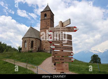 Hafling, Südtirol, Italien 07. Giu 2024: Hier der Blick auf das Kirchlein, Kirche St. Kathrein, Chiesa di Santa Caterina bei Hafling oberhalb von Merano, Kleinod, Wandern, spazieren, Ausblick, Natur, Meraner Land, Burggrafenamt, Pferdeparadies, Herkunft der Haflinger Pferde, im Vordergrund einige Wegweiser *** Hafling, alto Adige, Italia 07 giugno 2024 qui la vista della chiesetta, della Chiesa di San Kathrein, della Chiesa di Santa Caterina vicino Hafling sopra Merano, gemma, escursioni, camminate, vista, vista, natura, Terra di Meraner, Burggrafenamt, paradiso dei cavalli, origine dei cavalli Haflinger, in primo piano alcuni s Foto Stock