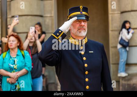 Il direttore della banda di cavalleria saluta durante l'inno nazionale sulla Schlossplatz. Altrimenti, rimane discreto nel mezzo del pubblico. Cerimonia della Guardia reale presso il Palazzo reale di Stoccolma. Cambio della guardia di fronte al Palazzo reale svedese di Stoccolma con accompagnamento musicale della banda montata. Yttre borggården, Stoccolma, Svezia Foto Stock