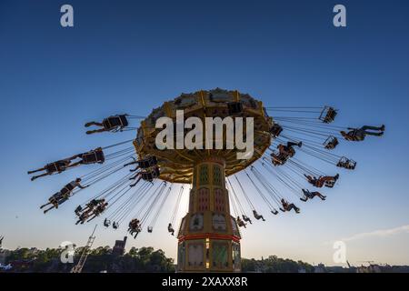 Gröna Lund sull'isola museo di Djurgården è il più antico parco divertimenti della Svezia ed è stato fondato nel 1883 dal tedesco Jacob Schultheiss. Il parco divertimenti è diviso in una parte vecchia e una nuova. Qui la giostra a catena nostalgica al sole della sera. Si trova direttamente sull'acqua. Carosello a catena a Gröna Lund Tivoli. Parco divertimenti stagionale con montagne russe e giostre emozionanti, giochi competitivi e concerti dal vivo. Djurgårdsstaden, Stoccolma, Svezia Foto Stock