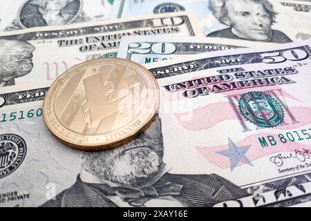 Primo piano su una moneta litecoin dorata in cima a una pila di dollari americani. Foto Stock