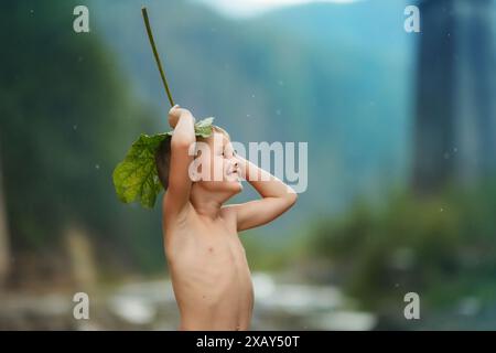 Un ragazzo che si nasconde dalla pioggia sotto un molo Foto Stock