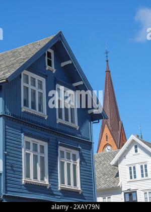 Casa in legno blu con finestre bianche di fronte a una torre rossa sotto un cielo blu brillante, Haugesund, Norvegia Foto Stock