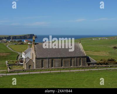 Chiesa rurale affacciata sul mare tra campi e prati sotto un cielo blu, Lerwick, Shetland, Scozia, Regno Unito Foto Stock