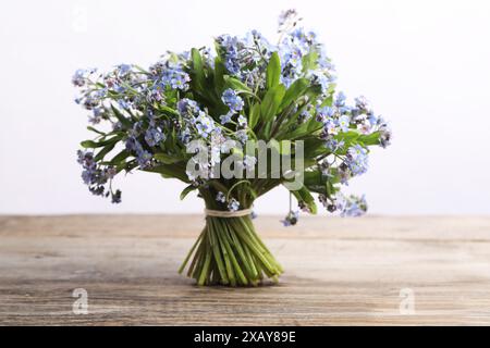 Bouquet di bellissimi fiori dimenticati su un tavolo di legno su sfondo bianco Foto Stock