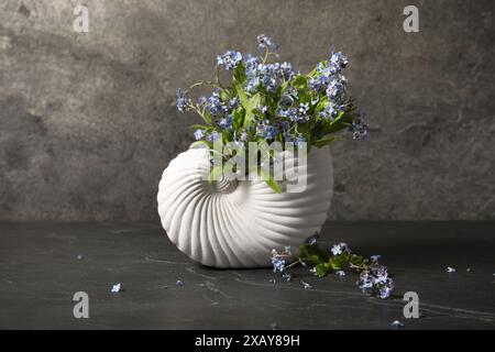 Bouquet di bellissimi fiori "dimentica" in vaso su un tavolo testurizzato grigio Foto Stock
