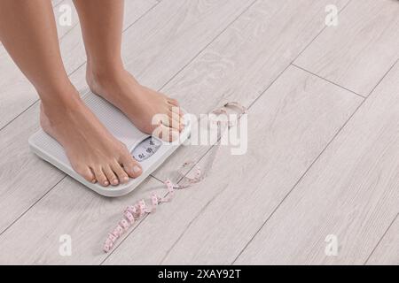 Donna in piedi su una scala e un metro a nastro a casa, primo piano. Spazio per il testo Foto Stock