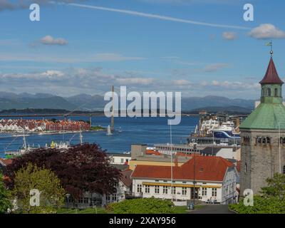 Vista sulla città con porto, edifici e un ponte di fronte a una montagna sullo sfondo sotto un cielo blu, stavanger, norvegia Foto Stock