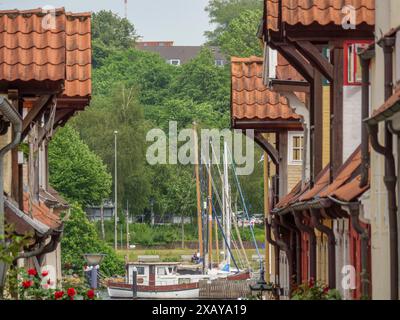 Vista attraverso il vicolo stretto con case a graticcio e barche nel porto, circondato da una vegetazione lussureggiante, Flensburg, Schleswig-Holstein Foto Stock
