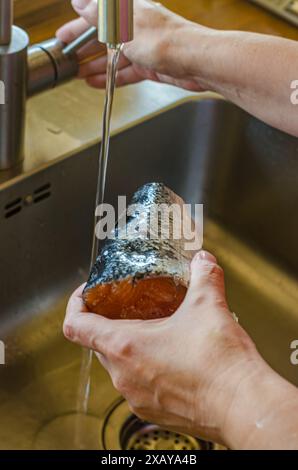 Le donne puliscono e lavano parte del salmone con le mani. Foto di alta qualità Foto Stock