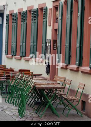 Accogliente caffetteria con tavoli verdi e sedie, in un edificio con persiane chiuse lungo la strada, speyer, Germania Foto Stock