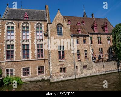 Edifici storici con facciate in mattoni lungo un canale sotto un cielo azzurro, Bruges, Belgio Foto Stock