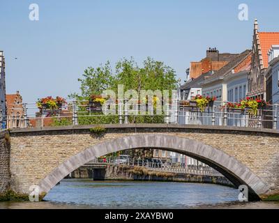 Ponte in pietra su un canale, decorato con fiori, circondato da edifici storici, Bruges, Belgio Foto Stock