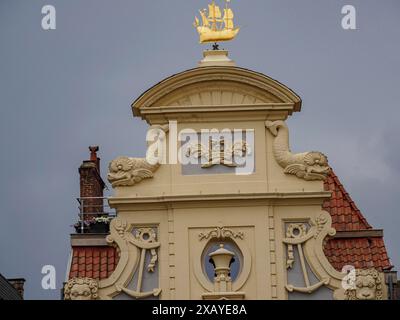 Vista dettagliata di un edificio con decorazioni dorate e uno stemma. Cielo nuvoloso grigio, Gand, Belgio Foto Stock