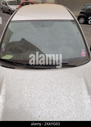 Cremona, Italia - 9 giugno 2024 l'auto d'argento parcheggiata su una strada cittadina è coperta da uno spesso strato di polvere dopo una tempesta di sabbia Foto Stock