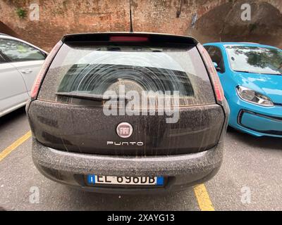 Cremona, Italia - 9 giugno 2024 la Dusty black car in città ha bisogno di essere pulita, somigliando a una tempesta di sabbia del deserto con sfumature grigie, marroni e bianche Foto Stock