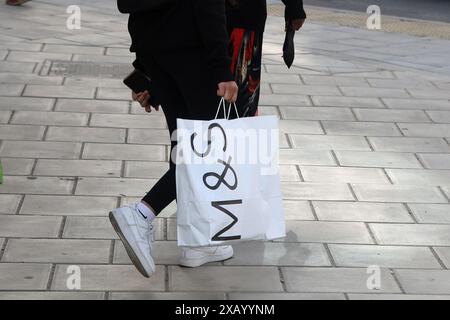 Un acquirente con un sacchetto di carta Marks & Spencer Foto Stock