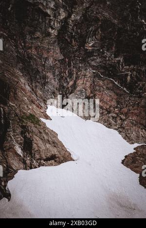 Vista ravvicinata dell'aspra parete rocciosa del ghiacciaio dell'Alaska con macchie di neve, evidenziando il contrasto netto e la bellezza selvaggia dei paesaggi incontaminati della natura Foto Stock