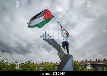 Rotterdam, Olanda meridionale, Paesi Bassi. 9 giugno 2024. Un manifestante, sulla cima di una statua, sventola una bandiera della Palestina. Il 9 giugno 2024, protestando contro le recenti misure e la violenza di Rafah da parte di Israele, i manifestanti filo-palestinesi hanno marciato attraverso Rotterdam, Paesi Bassi. (Credit Image: © James Petermeier/ZUMA Press Wire) SOLO PER USO EDITORIALE! Non per USO commerciale! Foto Stock