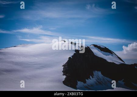 Questa splendida fotografia mostra una cresta incontaminata e innevata in Alaska, adagiata su un cielo blu vibrante con nuvole di neve. Perfetto per catturare t Foto Stock