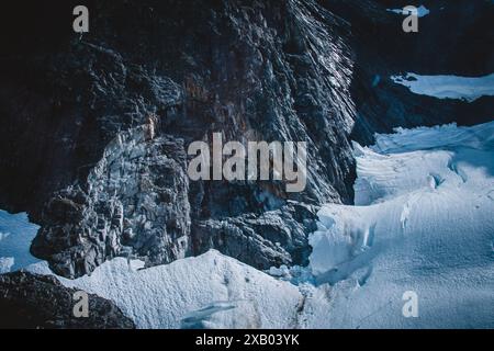 Questo incredibile scatto aereo cattura l'aspra bellezza di una scogliera glaciale dell'Alaska, evidenziando il drammatico contrasto tra la roccia scura e l'incontaminata Foto Stock