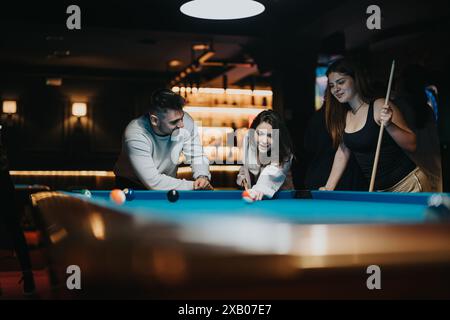 Amici che si divertono a giocare a biliardo in un bar poco illuminato Foto Stock