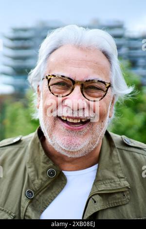 Ritratto di un uomo anziano caucasico maturo felice in piedi all'aperto con giardino di sfondo non focalizzato. Foto Stock