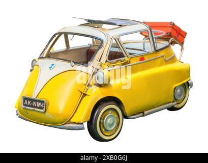 Riproduzione isolata di un'auto retrò di colore giallo indipendente simile a una BMW Isetta, agganciata su uno sfondo bianco e dotata di tettuccio apribile con una lu Foto Stock